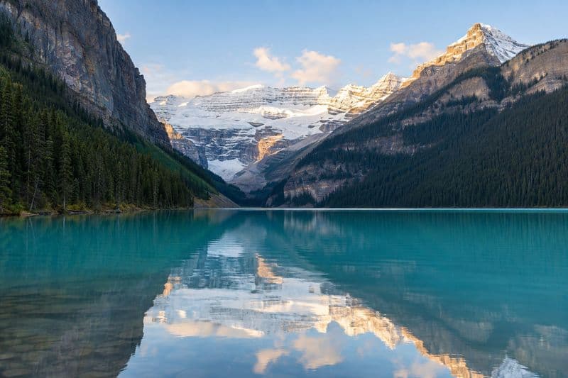 Lake Louise in still morning light, the turquoise water reflecting Victoria Glacier at the far end.